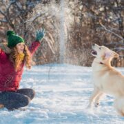 woman playing with dog in snow