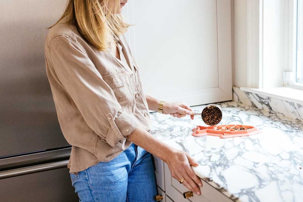 woman pouring cat food into feeder